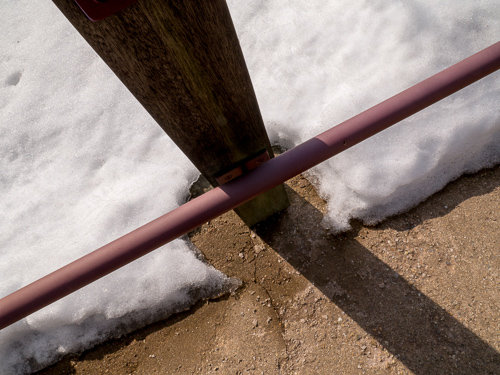 closeup of railing, looking down at snow and shadow